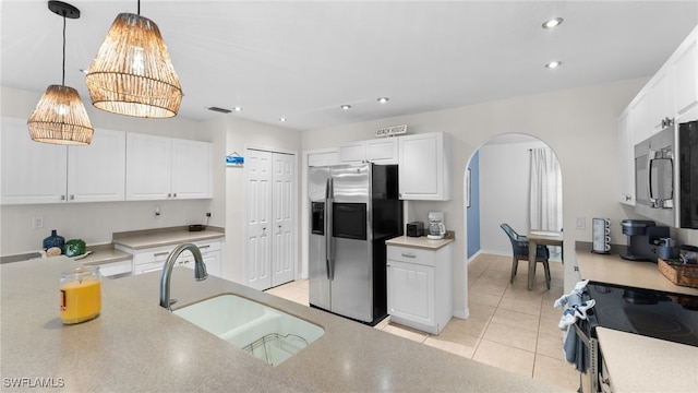 kitchen featuring white cabinets, hanging light fixtures, sink, light tile patterned floors, and appliances with stainless steel finishes