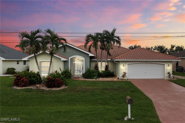 view of front facade featuring central air condition unit, a garage, and a lawn