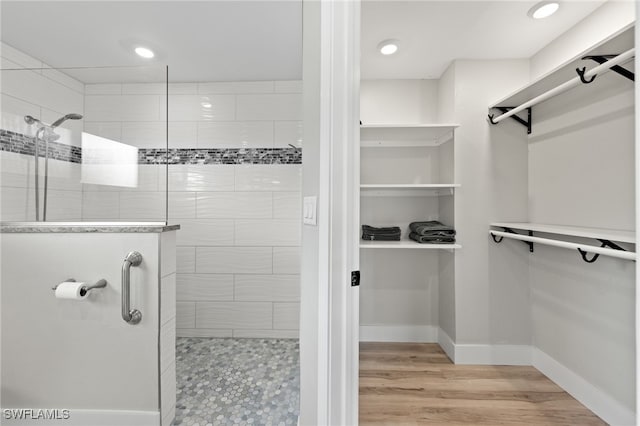 bathroom with hardwood / wood-style flooring and tiled shower