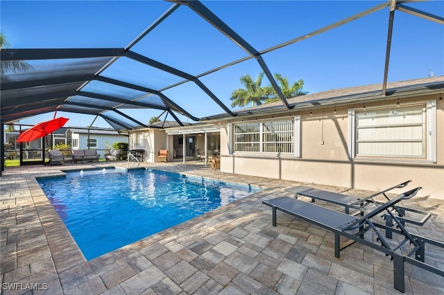 view of pool with glass enclosure and a patio area