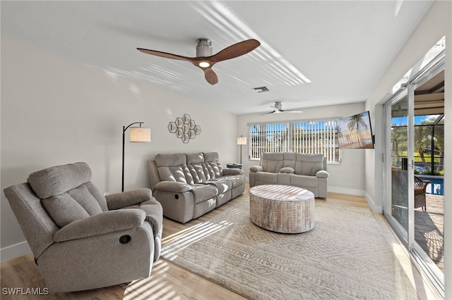 living room featuring light hardwood / wood-style floors, ceiling fan, and a wealth of natural light