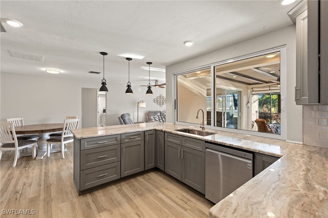 kitchen featuring light wood-type flooring, dishwasher, sink, kitchen peninsula, and hanging light fixtures