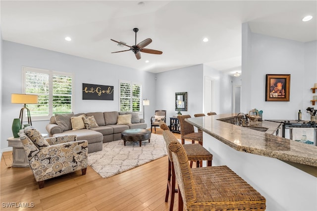 living room with light hardwood / wood-style floors, ceiling fan, and sink