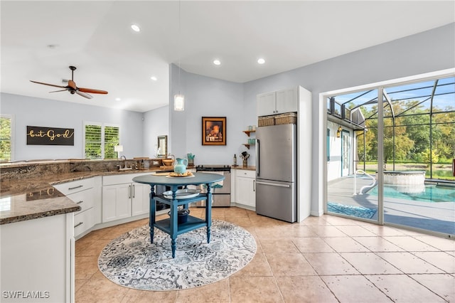 kitchen featuring kitchen peninsula, sink, white cabinetry, appliances with stainless steel finishes, and dark stone counters