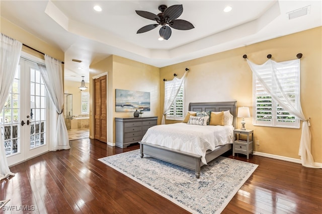 bedroom with multiple windows, a raised ceiling, ceiling fan, and dark wood-type flooring