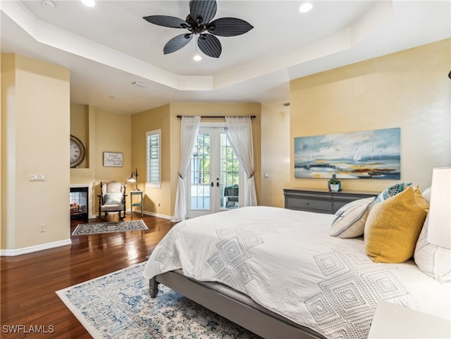 bedroom featuring ceiling fan, a raised ceiling, french doors, dark wood-type flooring, and access to exterior