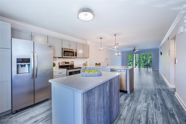 kitchen with sink, crown molding, stainless steel appliances, decorative light fixtures, and kitchen peninsula