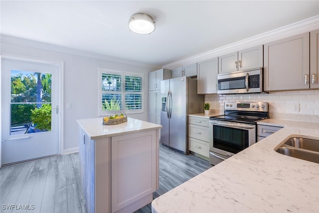 kitchen with gray cabinetry, light stone counters, tasteful backsplash, ornamental molding, and stainless steel appliances