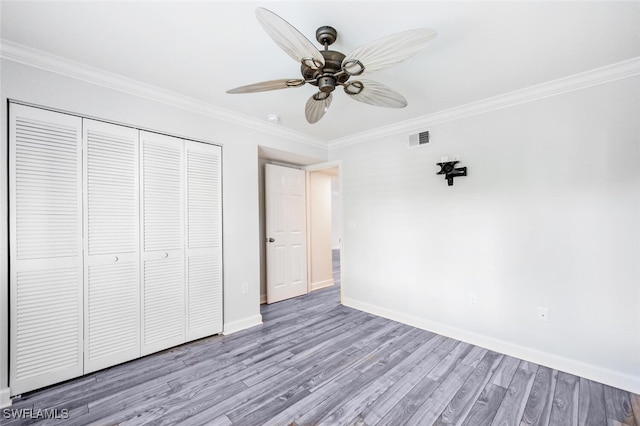 unfurnished bedroom with ornamental molding, a closet, ceiling fan, and light hardwood / wood-style flooring