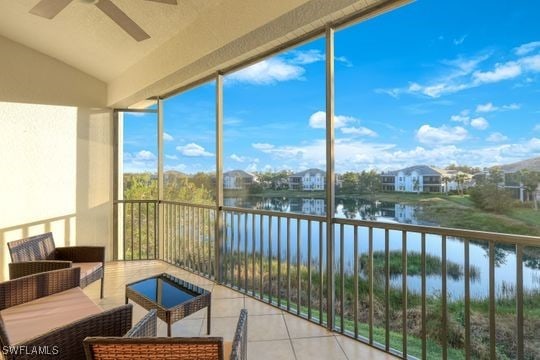 sunroom / solarium featuring ceiling fan and a water view