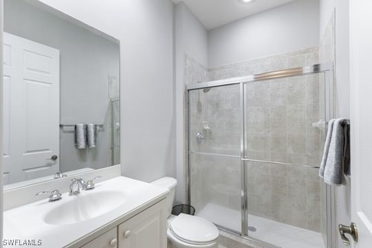 bathroom featuring vanity, an enclosed shower, and toilet