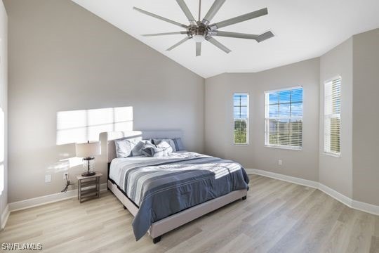 bedroom with ceiling fan, vaulted ceiling, and light hardwood / wood-style flooring