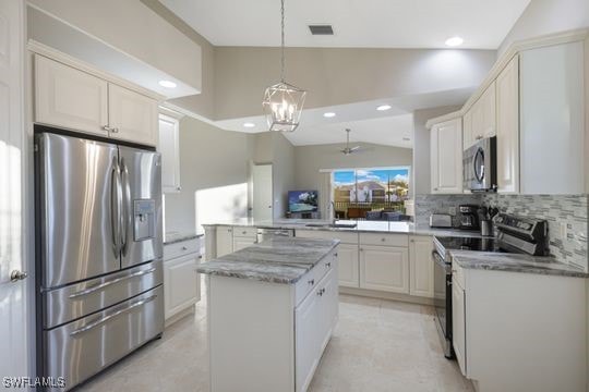 kitchen featuring a center island, backsplash, vaulted ceiling, appliances with stainless steel finishes, and kitchen peninsula