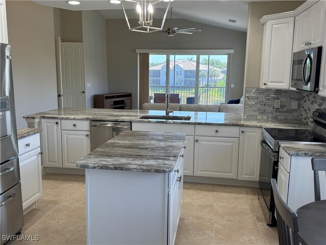 kitchen with a sink, lofted ceiling, decorative backsplash, a kitchen island, and appliances with stainless steel finishes