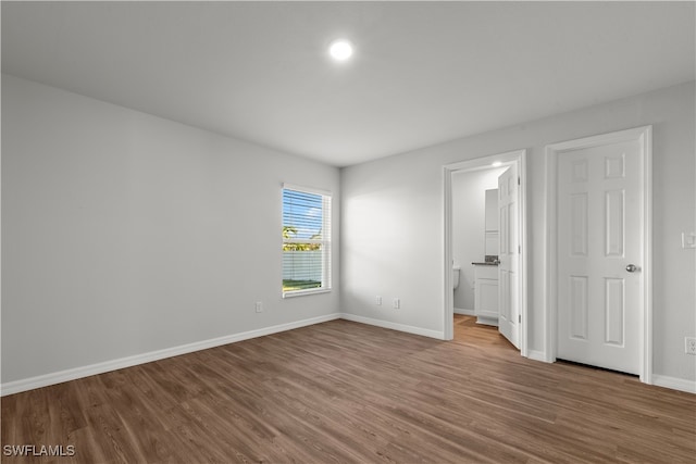 unfurnished bedroom featuring ensuite bath and wood-type flooring