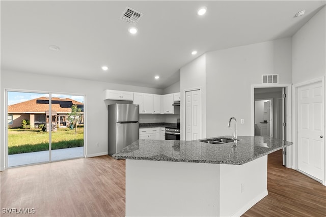 kitchen with light wood-type flooring, stainless steel appliances, sink, dark stone countertops, and white cabinets