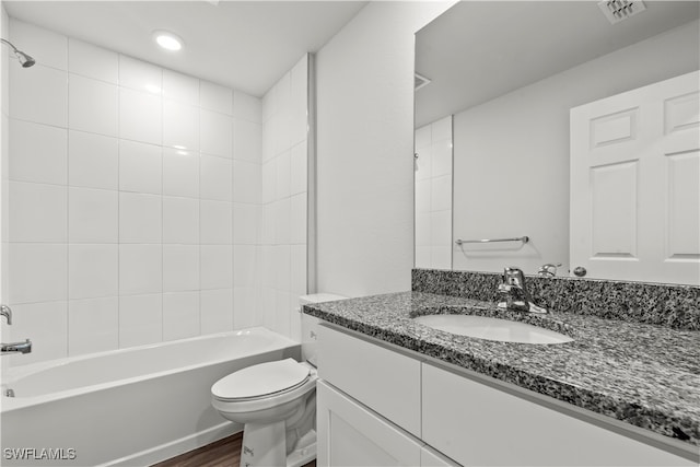 full bathroom featuring vanity, wood-type flooring, tiled shower / bath combo, and toilet