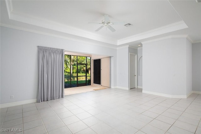 empty room featuring ornamental molding, a tray ceiling, baseboards, and light tile patterned floors