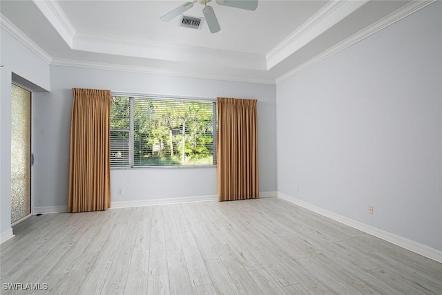 empty room featuring visible vents, a raised ceiling, wood finished floors, and ornamental molding