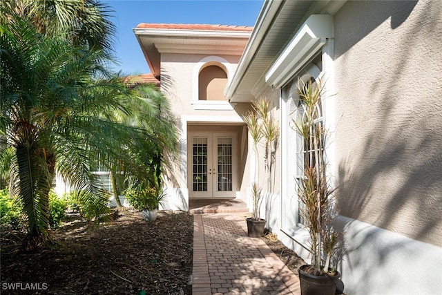 property entrance with french doors, a tiled roof, and stucco siding