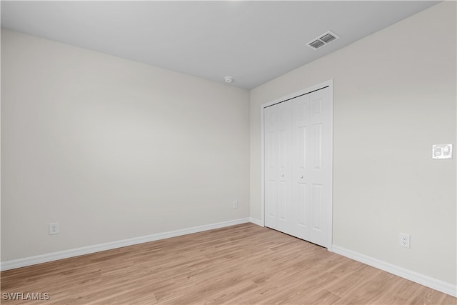 unfurnished bedroom with light hardwood / wood-style flooring and a closet