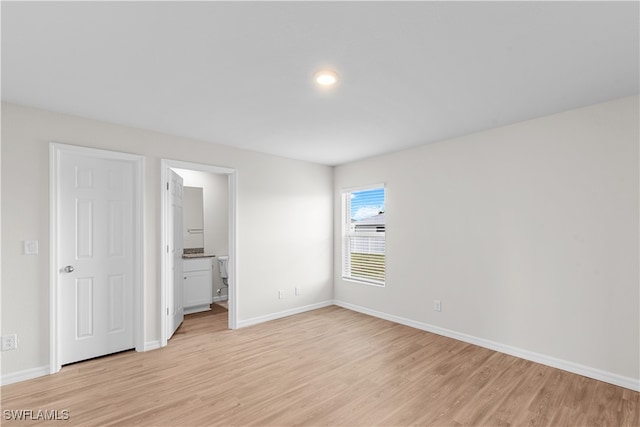 unfurnished bedroom with ensuite bath and light wood-type flooring