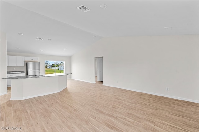 unfurnished living room featuring lofted ceiling and light hardwood / wood-style floors