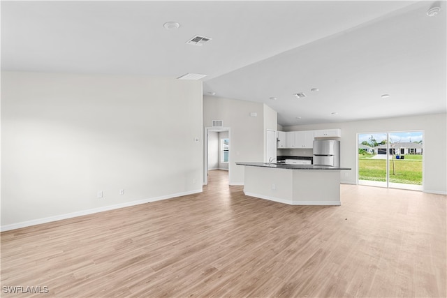 kitchen featuring white cabinets, light hardwood / wood-style floors, lofted ceiling, and stainless steel fridge