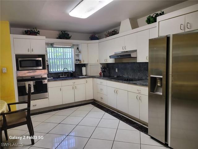 kitchen featuring tasteful backsplash, sink, white cabinetry, appliances with stainless steel finishes, and light tile patterned floors