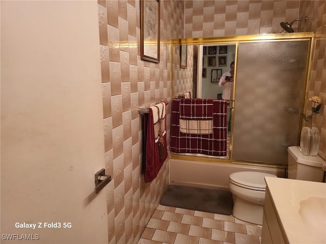 full bathroom with enclosed tub / shower combo, tile walls, vanity, and toilet