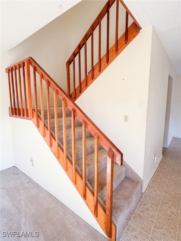 stairs with carpet flooring and a textured ceiling