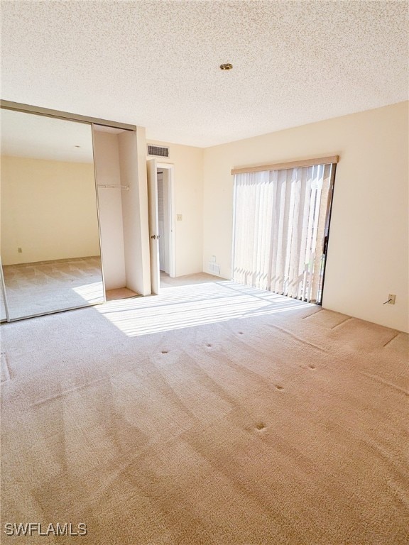 unfurnished room featuring a textured ceiling and light carpet