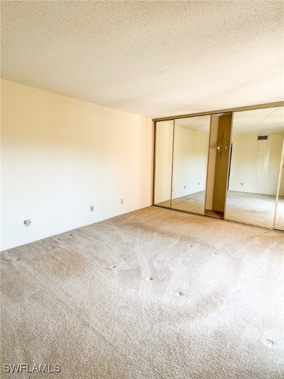 unfurnished bedroom featuring carpet flooring, a textured ceiling, and a closet