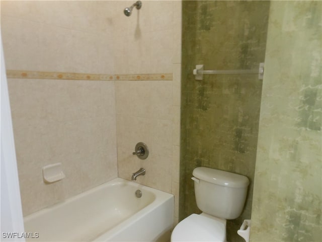 bathroom featuring tiled shower / bath combo and toilet