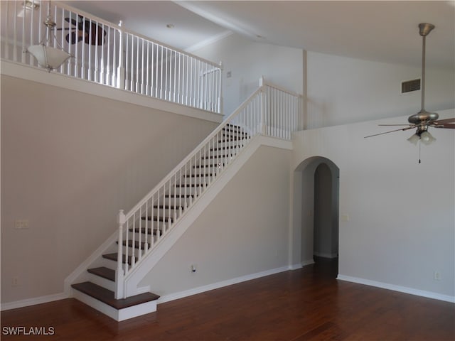 stairway with ceiling fan, hardwood / wood-style floors, and high vaulted ceiling