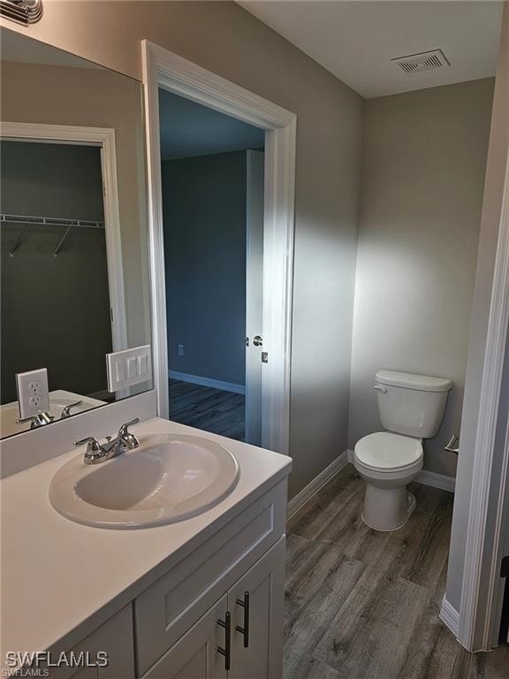 bathroom with wood-type flooring, vanity, and toilet