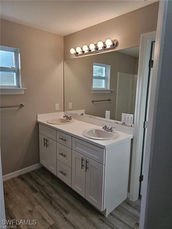 917 Martha Ave S, Lehigh Acres, FL 33974 - bathroom featuring double vanity, wood finished floors, and healthy amount of natural light
