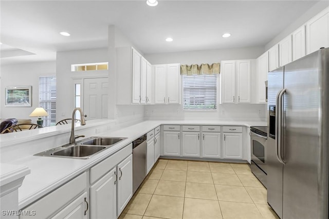 kitchen with appliances with stainless steel finishes, a sink, light tile patterned floors, white cabinets, and recessed lighting