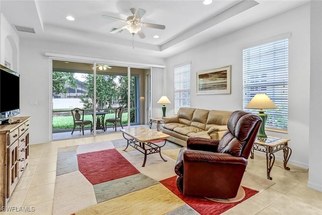 living area featuring a ceiling fan, a raised ceiling, light tile patterned flooring, recessed lighting, and baseboards