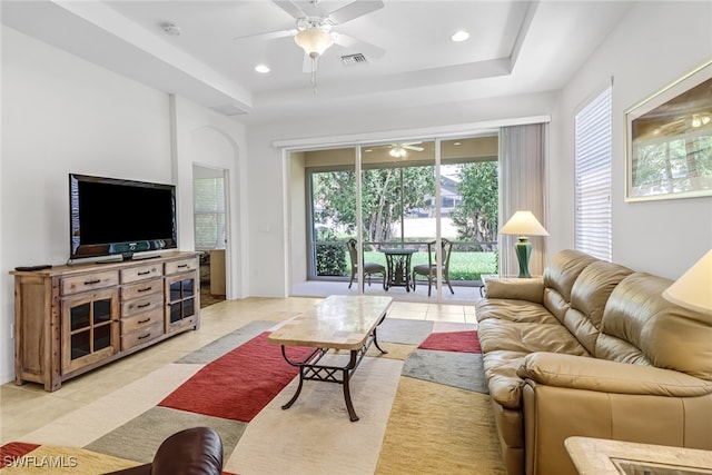 living area featuring ceiling fan, visible vents, a raised ceiling, and light tile patterned flooring