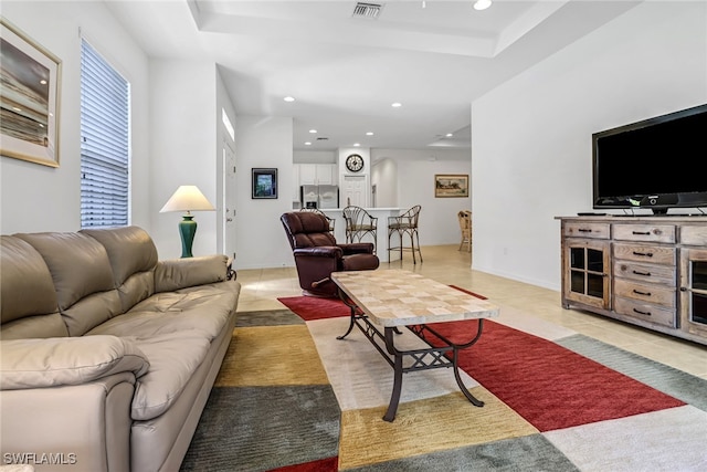 living room featuring visible vents, a raised ceiling, baseboards, light tile patterned flooring, and recessed lighting