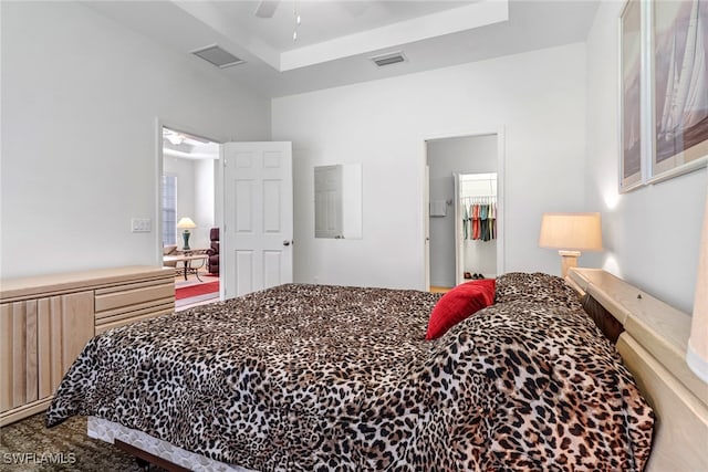 bedroom with a ceiling fan, visible vents, a tray ceiling, and carpet flooring