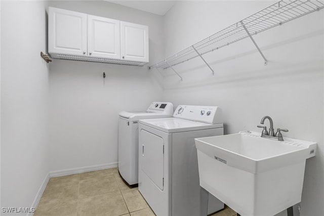 laundry room featuring cabinet space, light tile patterned flooring, a sink, washer and dryer, and baseboards