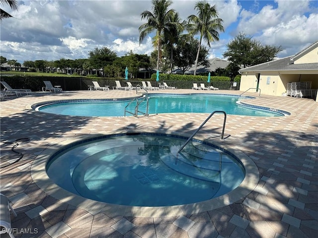 community pool featuring a patio area, fence, and a hot tub