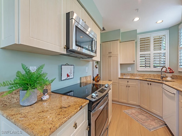 kitchen featuring light stone counters, light hardwood / wood-style floors, stainless steel appliances, and sink