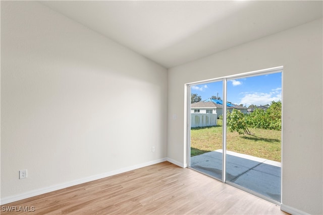 empty room featuring a wealth of natural light, lofted ceiling, and light hardwood / wood-style flooring