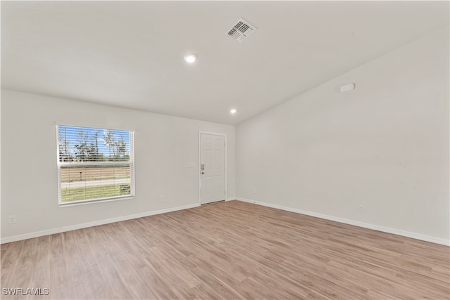 empty room with vaulted ceiling and light hardwood / wood-style floors