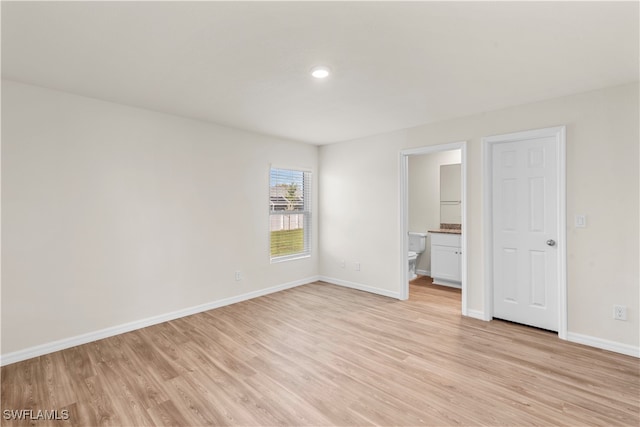 unfurnished bedroom with ensuite bath and light hardwood / wood-style floors