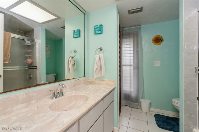 bathroom featuring vanity, tile patterned flooring, toilet, and a shower with door