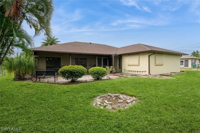 back of house featuring a lawn, a sunroom, and a fire pit